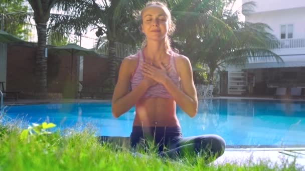 Ung dam sitter i Lotus pose sätta handflatorna på chestby pool — Stockvideo