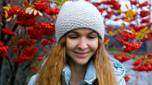 Blonde long haired girl in hat jacket smiles by rowan trees — Stock Video