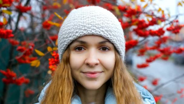 Blonde fille au chapeau sourit par les arbres de rowan dans la neige tombante — Video