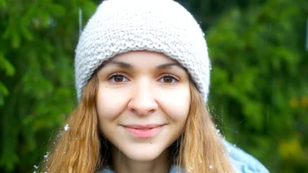 Flocons de neige tombent sur le chapeau et les cheveux blonds fille contre l'arbre à fourrure — Video