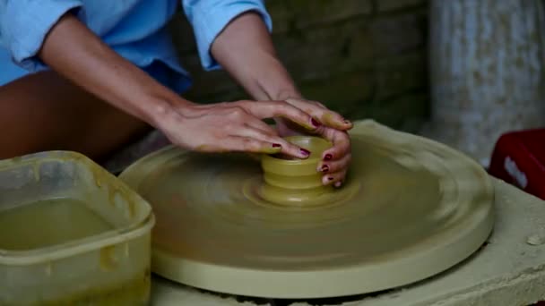 Chica de primer plano hace olla de arcilla en la rueda de alfarero en la tienda de cerámica — Vídeos de Stock