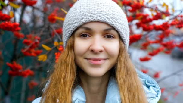 Ξανθιά κοπέλα στο πλεκτό καπέλο θέτει στο δέντρο κόκκινο rowan μούρα — Αρχείο Βίντεο