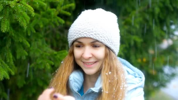 Menina com cabelo fluindo pega flocos de neve na mão em furtree — Vídeo de Stock