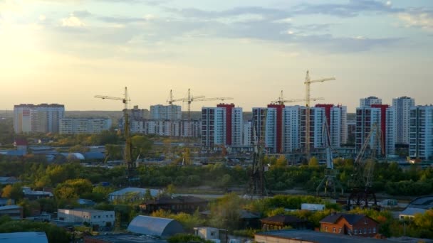 Grúas torre en el sitio buliding en la ciudad moderna contra el atardecer — Vídeo de stock