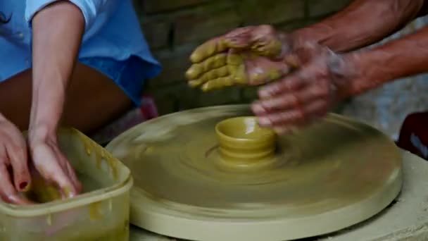表示を閉じる上級マスターは女の子レッスンで陶器のワーク ショップで轆轤を回転の粘土ポットを作成する方法を示します — ストック動画