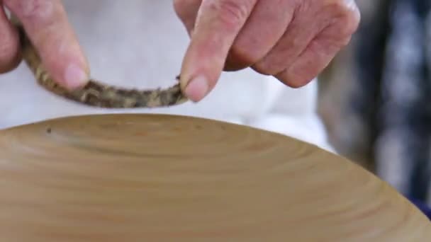 Closeup potter handen verwijderen klei overmaat uit pot bodem — Stockvideo