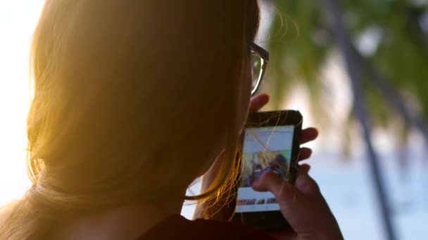 Primer plano espalda puesta del sol luces chica cabeza mirando el teléfono — Vídeo de stock