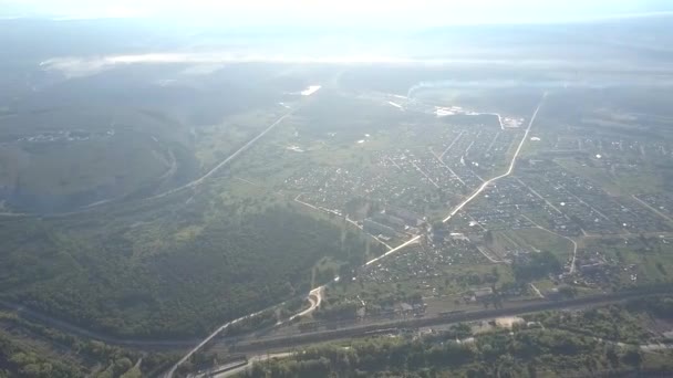 Vista aérea pequeña ciudad en verde valle bajo cielo ilimitado — Vídeo de stock