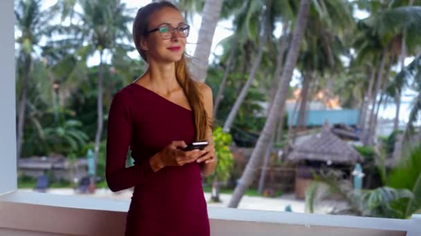 Fille en lunettes robe de soirée tient téléphone sur la terrasse — Video