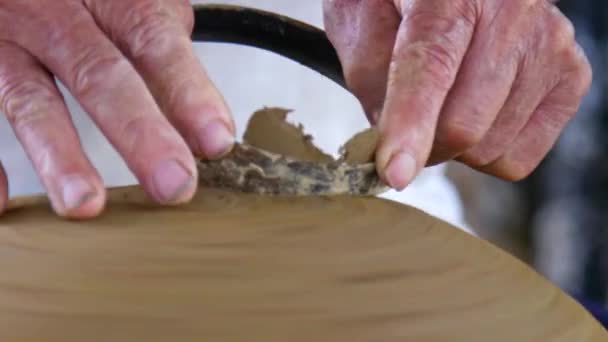 特写镜头熟练的亚洲陶工去除粘土多余的大湿锅与传统的金属环在商店 — 图库视频影像