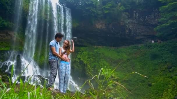 Mann langhaarige Mädchen machen Selfie gegen schäumenden Wasserfall — Stockvideo