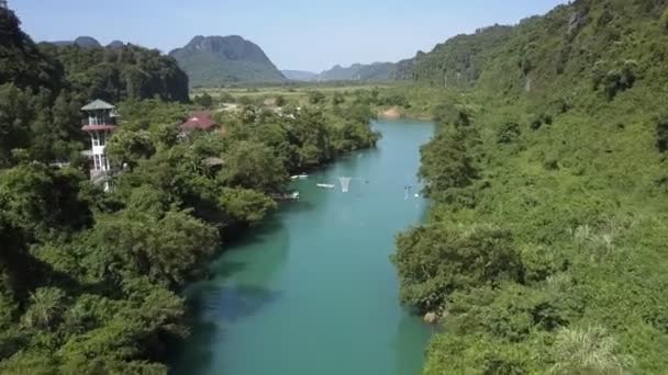 Movimiento a lo largo del estrecho río azul que fluye más allá del pueblo — Vídeos de Stock