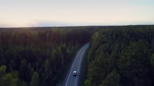 梦幻般的航拍图片太阳落后地平线以上的天空和汽车驾驶沿路通过黑暗的森林在晚上 — 图库视频影像