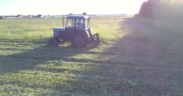 Техника с косилкой движется по полю отрезая траву — стоковое видео