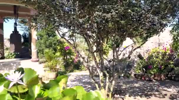 過去の大きな新鮮なユリの花を鍋寺領土に巨大な釣鐘と大理石の柱のパビリオンにモーション — ストック動画