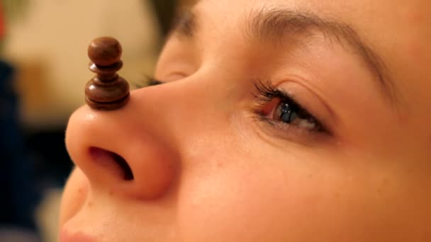 Macro pièce d'échecs pion noir se tient sur joli nez de fille — Video