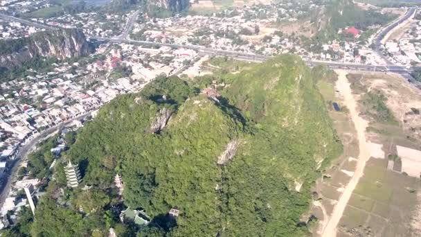 Vista de pájaro techos del templo en colina verde contra ciudad — Vídeo de stock
