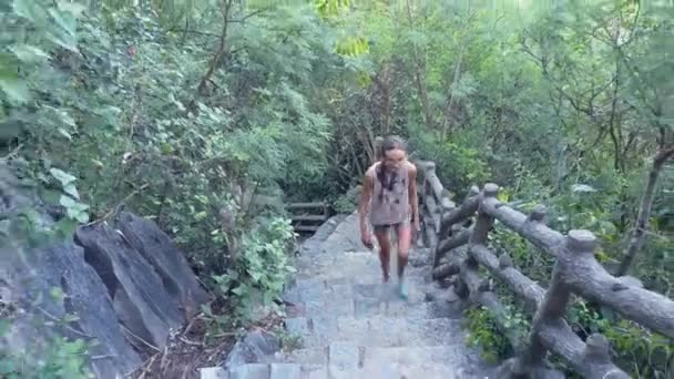女孩在被丛林覆盖的山上走上旧楼梯 — 图库视频影像