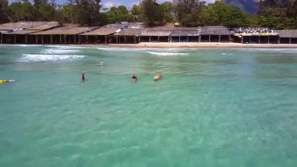 Toldos de playa por palmeras y surfistas en las olas del océano — Vídeos de Stock