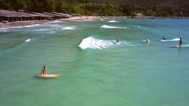 Dívka v červených plavkách se snaží sedět na surfovací prkno na mělké vodě — Stock video