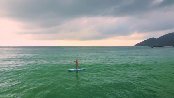 Donna cavalca surf su paddleboard tra oceano — Video Stock