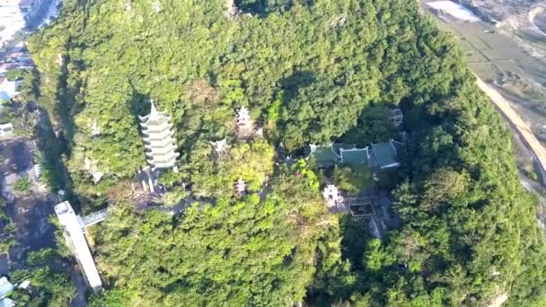 Flycam se levanta sobre el templo en la colina verde rodeada de ciudad — Vídeo de stock
