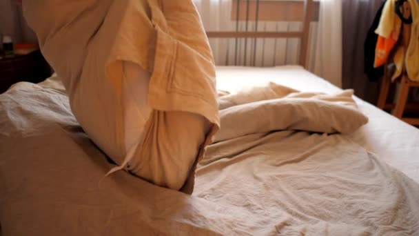 Persona lanza almohadas sacude manta que cubre cama doble — Vídeo de stock
