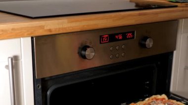 ağır çekim kadın ile pizza fırın tepsi fırına koyar.