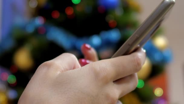 Fermez la main de fille de mouvement lent tient le téléphone par l'arbre de Noël 