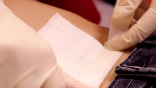 Мастер крупным планом чинит хлопчатобумажную салфетку на животе девушки с нашивкой — стоковое видео