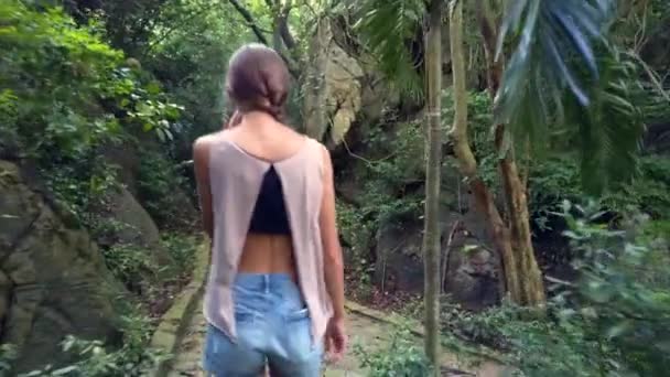 在茂密的公园里, 后面的女孩沿着古老的石轨走着 — 图库视频影像