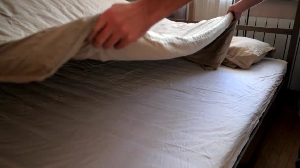 Iki çift kişilik yatak üzerinde yayılan adam el sallamak battaniye — Stok video