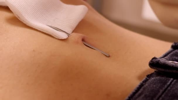Slow motion master inserts belly button ring into needle — Stock Video