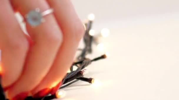 Macro chica manos fijar Navidad cadena de luces en la pared — Vídeo de stock