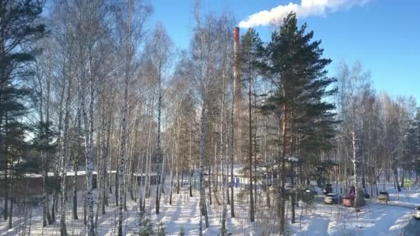 Cámara se eleva por encima de madera de nieve a la estación de calefacción con torres — Vídeos de Stock