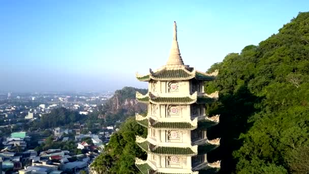 Zoom aéreo de pagoda entre los árboles verdes de la colina por ciudad — Vídeo de stock