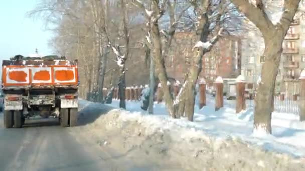Камера следует за грузовиком, проезжающим мимо домов на деревьях в зимний день — стоковое видео