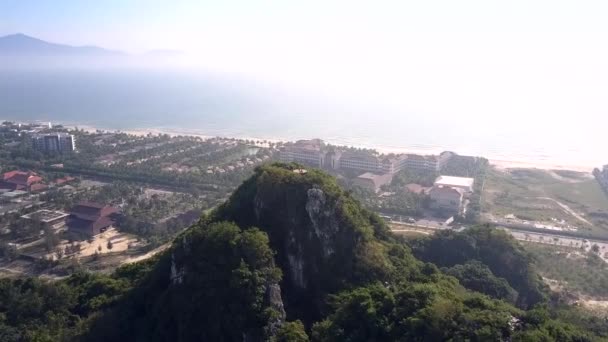 Montaña aérea con el hombre en la cima y la ciudad en la costa del océano — Vídeo de stock