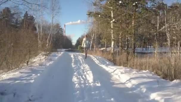 Воздушный низкоугольный выстрел девушка с сосновыми прогулками вдоль снежной трассы — стоковое видео