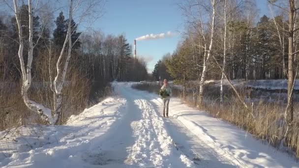 Aerial kvinna bär tall längs vägen är täckt av snö — Stockvideo