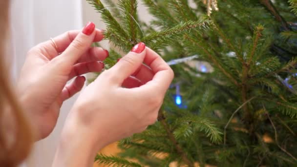 Lento movimento closeup mãos pendurar cone de ouro na árvore de Natal — Vídeo de Stock