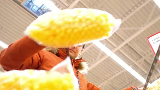 Alacsony szög lövés ember betölti a bevásárlókocsi kukorica labda csomagok — Stock videók
