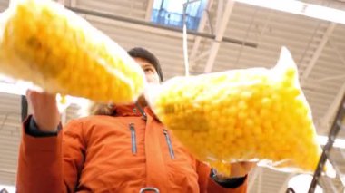 düşük açılı adamı vurdu büyük sarı mısır topu paketleri tutar.