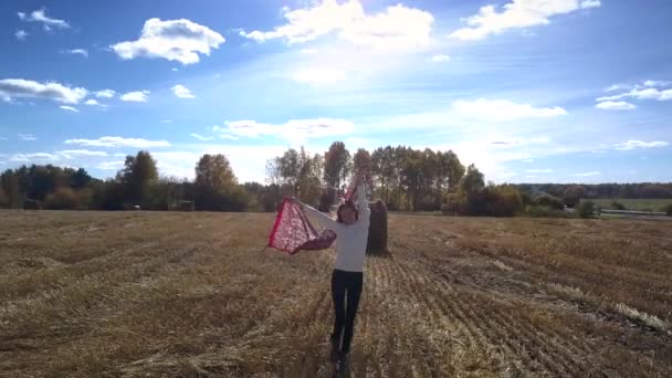 Upper shot woman with shawl stands by straw bale on field — Stock Video