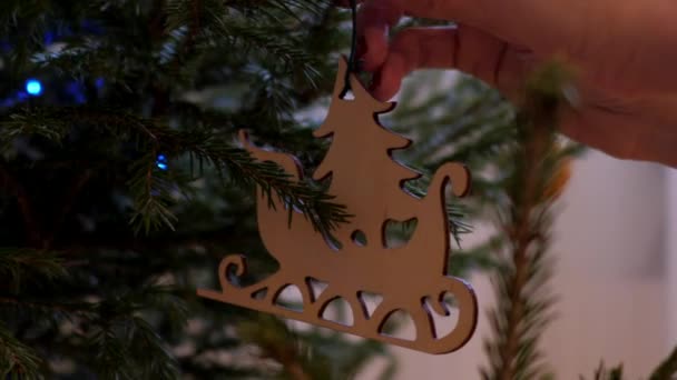 Frau in Zeitlupe schmückt Weihnachtsbaum mit Weihnachtsmann-Schlitten — Stockvideo