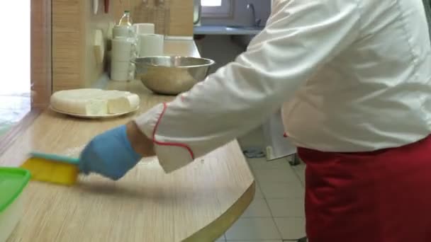 Primer plano cocinero en uniforme blanco limpia la harina de la mesa — Vídeos de Stock