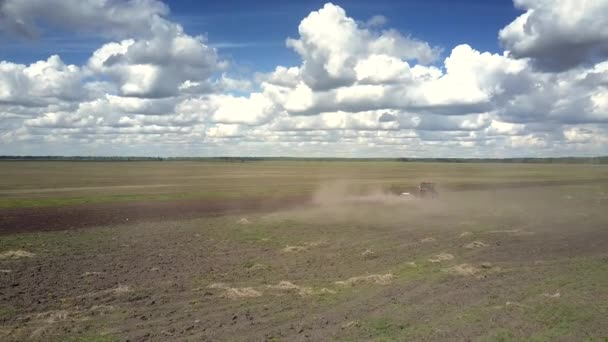 Vasto campo primaverile aratri trattore sollevando polvere e cielo blu — Video Stock