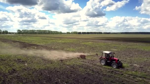 Trator aéreo puxa grade faz sulco de campo na nuvem de poeira — Vídeo de Stock
