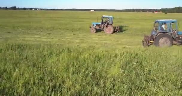 Presse da fieno si intersecano su un vasto campo falciatura erba coltivata — Video Stock