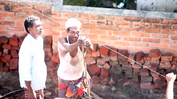 Trabalhadores tirar corda de gancho perto da parede de tijolo no jardim — Vídeo de Stock